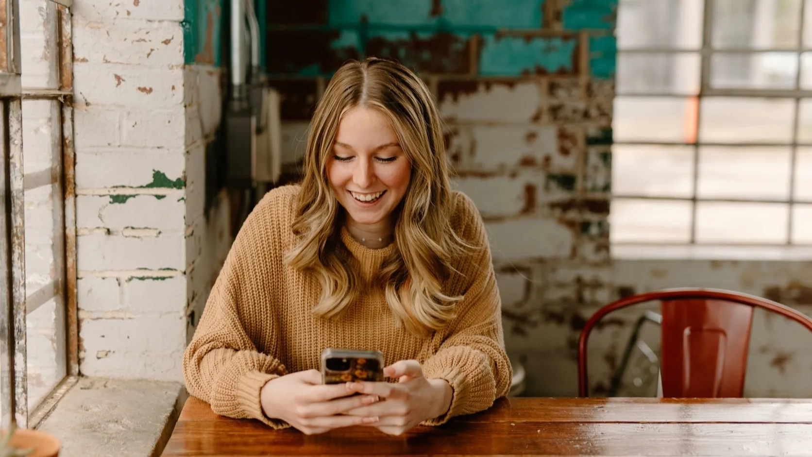 Woman smiling at her smartphone while texting at a modern bar